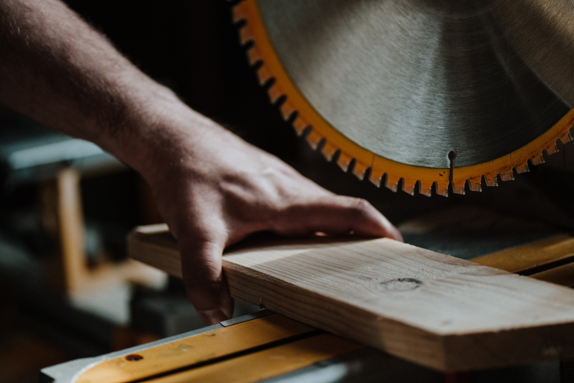 Man's hand working a saw and lumber